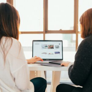 two women talking while looking at laptop computer